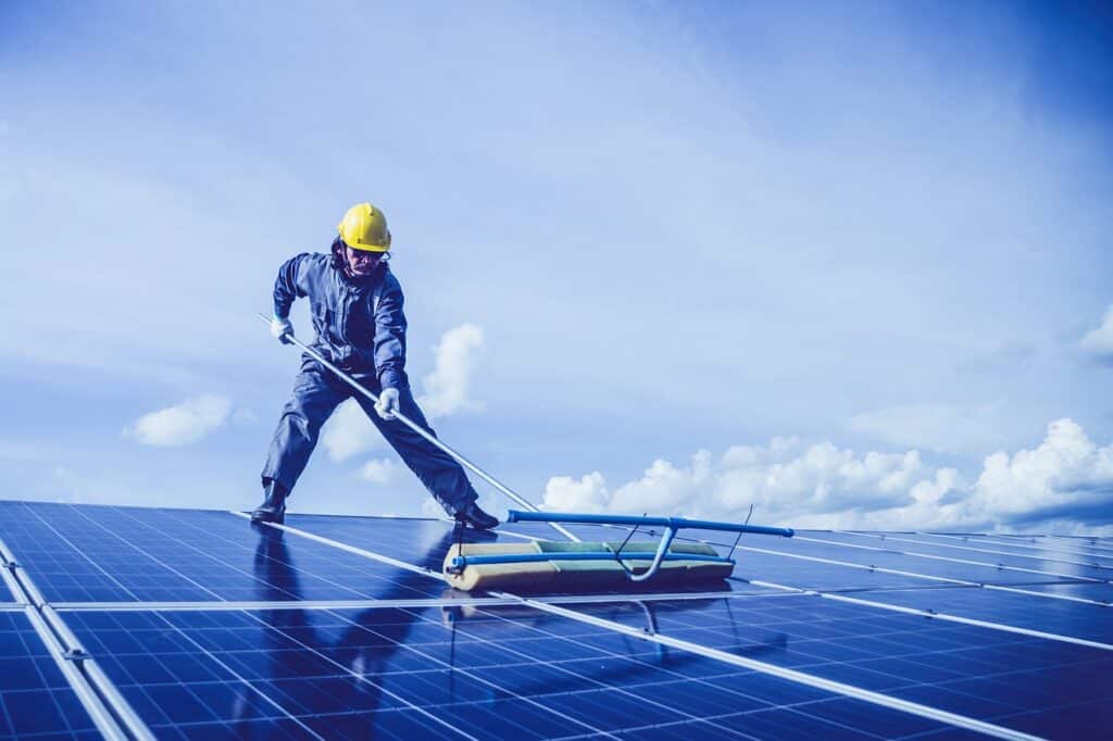man cleaning dirty solar panels